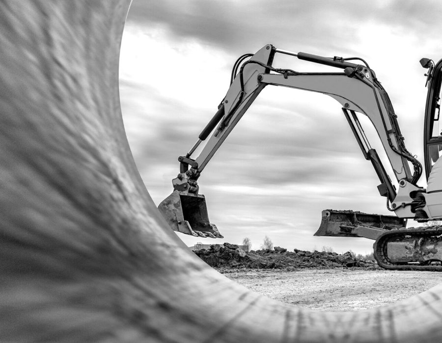 Mini excavator at the construction site on the edge of a pit against a cloudy blue sky. Compact construction equipment for earthworks. An indispensable assistant for earthworks